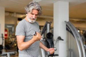 Homem com mais de 40 anos realizando exercício de bíceps na academia